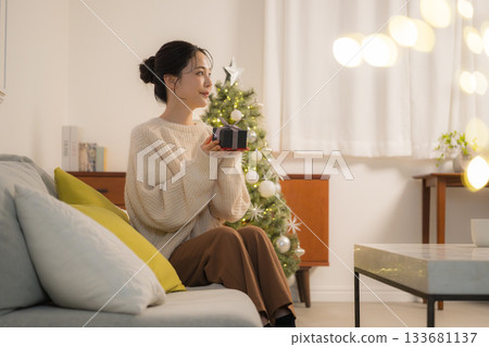 一位面帶微笑的女士手捧禮物,站在聖誕樹前,畫面充滿冬日節日氣氛。 一位面帶微笑的女士手捧禮物,站在聖誕樹前,畫面充滿冬日節日氣氛。 133681137