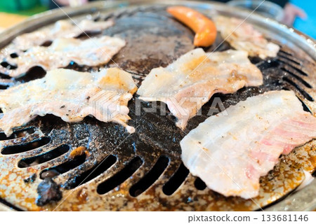 Thinly sliced meat and sausages grilled in a Genghis Khan pot (outdoor cooking) 133681146