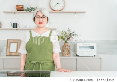 Senior Asian woman in an apron cooking in the kitchen at home 133681396