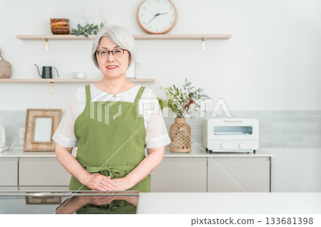 Senior Asian woman in an apron cooking in the kitchen at home 133681398