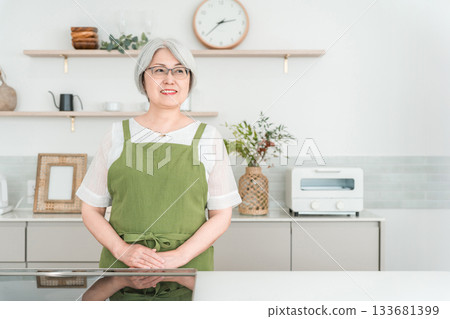 Senior Asian woman in an apron cooking in the kitchen at home 133681399
