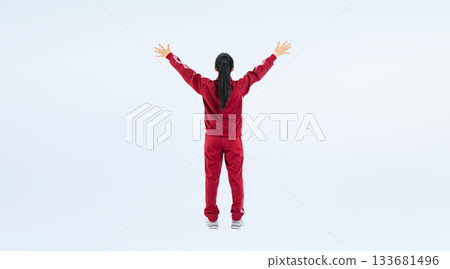 Full-body photo of a female student in a gym jersey raising her arms in a cheer Full-body photo of a female student in a gym jersey raising her arms in a cheer 133681496