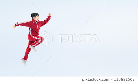 Full-body photo of a female student wearing a gym jersey jumping energetically Full-body photo of a female student wearing a gym jersey jumping energetically 133681502