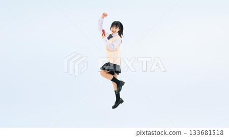 一張身穿校服的女學生手持智慧型手機跳躍的全身照。 一張身穿校服的女學生手持智慧型手機跳躍的全身照。 133681518