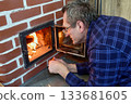 Wood stove heating country house middle aged man maintains fire brick wood burning stove. 133681605