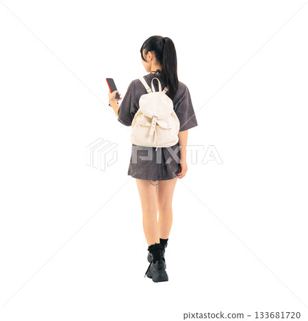 A teenage girl walking while looking at her smartphone. A hand-cut, transparent, full-body PNG photo. 133681720