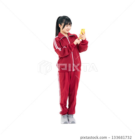 身穿運動服的女學生正在使用智慧型手機。全身PNG照片，透明背景，手工精準摳圖。 133681732
