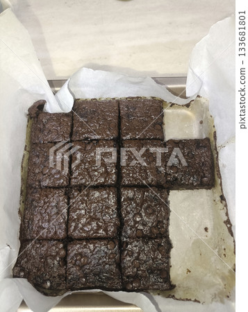 Chocolate brownie tray bake with parchment and cut squares, rich homemade dessert with glossy top Chocolate brownie tray bake with parchment and cut squares, rich homemade dessert with glossy top 133681801