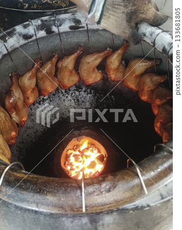 Roasted chicken legs hanging inside charcoal oven with warm glowing fire, savory and rustic aroma Roasted chicken legs hanging inside charcoal oven with warm glowing fire, savory and rustic aroma 133681805