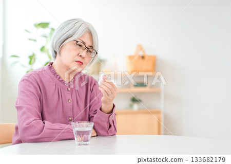 一位銀髮老婦人正在檢查藥瓶的劑量和容量。 一位銀髮老婦人正在檢查藥瓶的劑量和容量。 133682179