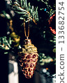The green Christmas tree is decorated with gold baubles and glittering ornaments, creating vibrant reflections and a winter holiday atmosphere. 133682754