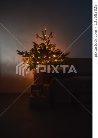 Small christmas tree with natural decorations and gift boxes with warm evening light 133682829