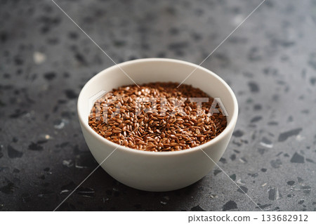 Flax seeds in white bowl on terrazzo surface with copy space Flax seeds in white bowl on terrazzo surface with copy space 133682912