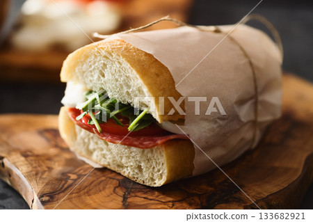 ciabatta sandwich with salami and mozzarella cheese on walnut table ciabatta sandwich with salami and mozzarella cheese on walnut table 133682921