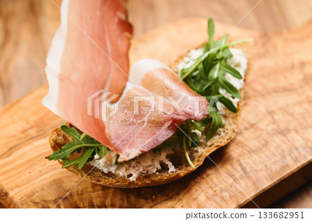 making of italian sandwich with speck and arugula making of italian sandwich with speck and arugula 133682951