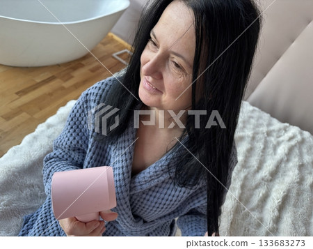 Woman Drying Hair With Compact Pink Hair Dryer at Home, Daily Beauty Routine in Cozy Bathrobe Woman Drying Hair With Compact Pink Hair Dryer at Home, Daily Beauty Routine in Cozy Bathrobe 133683273