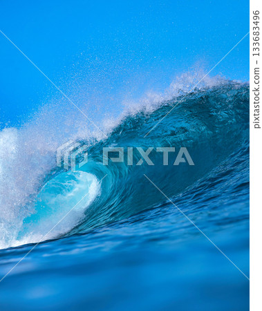 Majestic ocean swell with shimmering sunlight and foamy crest 133683496