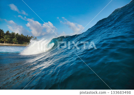 Energetic surf soaring over coral reef with dazzling sunlight reflections 133683498