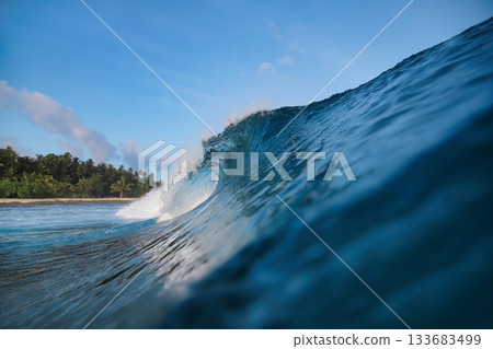 Energetic surf soaring over coral reef with dazzling sunlight reflections 133683499