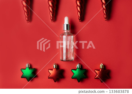 Cosmetic serum in glass bottle on red background with Christmas toys 133683878