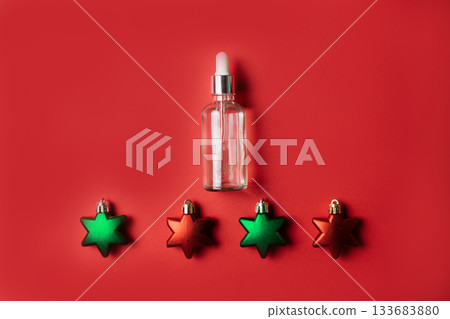 Cosmetic serum on red background with star shaped Christmas decorations Cosmetic serum on red background with star shaped Christmas decorations 133683880
