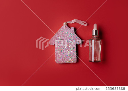 Cosmetic serum on red background with Christmas house ornament 133683886