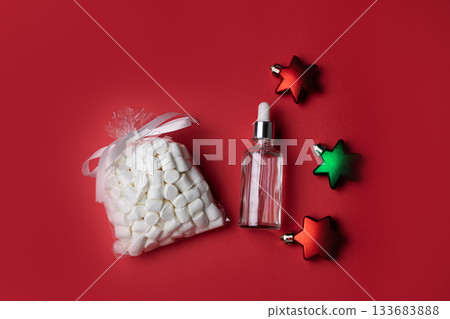 Marshmallows, cosmetic serum and star shaped ornaments on red background 133683888