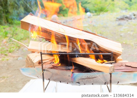 Fire and smoke from firewood burning in a campfire 133684314