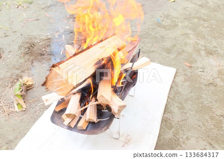 Fire and smoke from firewood burning in a campfire Fire and smoke from firewood burning in a campfire 133684317