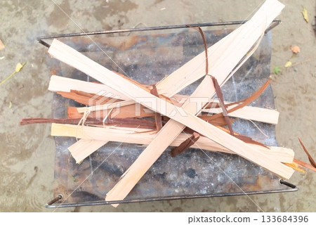 戶外場景，火坑堆放著柴火，人們正準備生火。 133684396