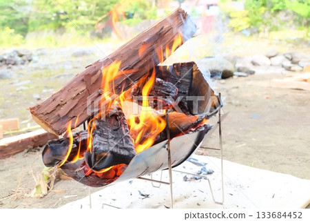 Outdoor scene of firewood and flames burning in a campfire 133684452