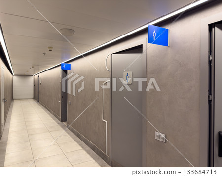 Modern hallway with doors to men and women restrooms. Separate restrooms with gender symbols. Grey public space interior with toilet entrances Modern hallway with doors to men and women restrooms. Separate restrooms with gender symbols. Grey public space interior with toilet entrances 133684713
