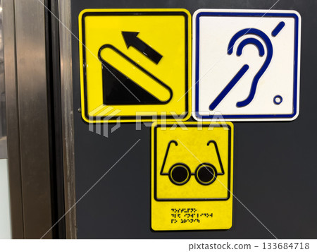 Escalator symbol with directions for people with disabilities. Crossed out ear symbol indicates accessible space for people with hearing problem. Sign with braille for blind allows for finger reading 133684718