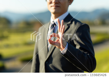 A middle-aged male businessman wearing a suit standing outdoors 133685426