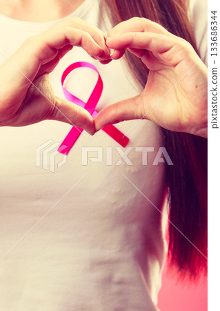 Breast cancer. Female hands make heart on pink ribbon 133686344