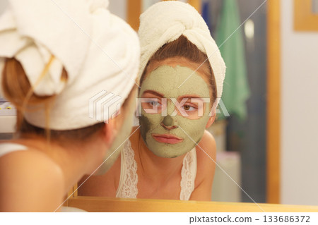 Woman removing facial clay mud mask in bathroom Woman removing facial clay mud mask in bathroom 133686372