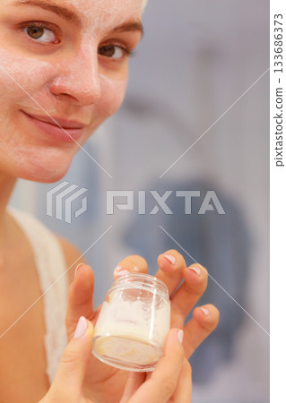 Woman applying mask cream on face in bathroom 133686373