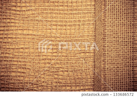Jute ribbon on burlap cloth background Jute ribbon on burlap cloth background 133686572