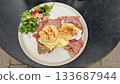 A plate of Eggs Benedict on the toast and bacon with salad 133687944
