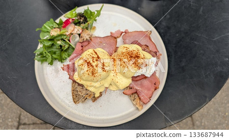 A plate of Eggs Benedict on the toast and bacon with salad A plate of Eggs Benedict on the toast and bacon with salad 133687944
