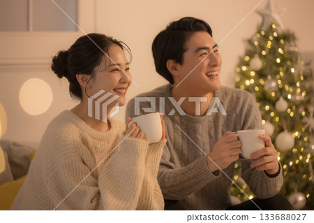 A cute couple spending time in a room with yellow lights like incandescent lights at night, Christmas tree and winter. TV and other media A cute couple spending time in a room with yellow lights like incandescent lights at night, Christmas tree and winter. TV and other media 133688027