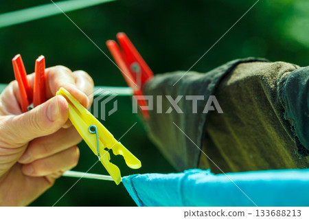 Woman hand hanging wet clothes on rope line 133688213
