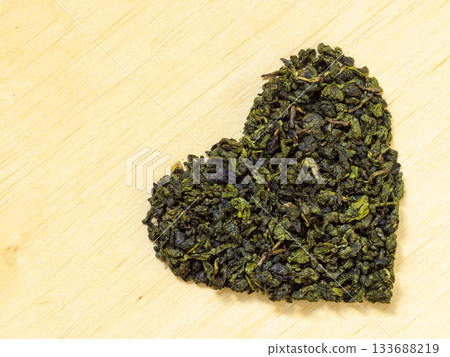 Green tea leaves heart shaped on wooden surface Green tea leaves heart shaped on wooden surface 133688219