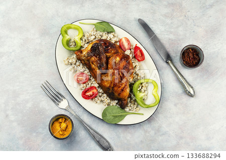 Half grilled chicken on the grill served with porridge. Half grilled chicken on the grill served with porridge. 133688294