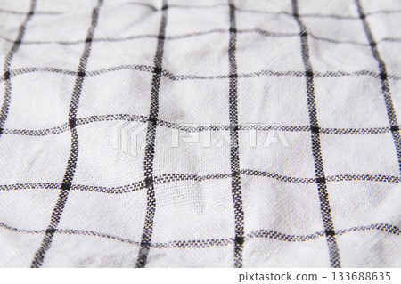 Plaid material. Towel on the table. Wrinkled fabric with stripes. Plaid material. Towel on the table. Wrinkled fabric with stripes. 133688635