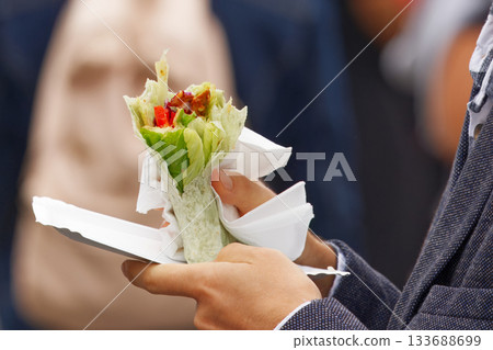Man holding vegan vegetable wrap at farmers market in Prague 133688699