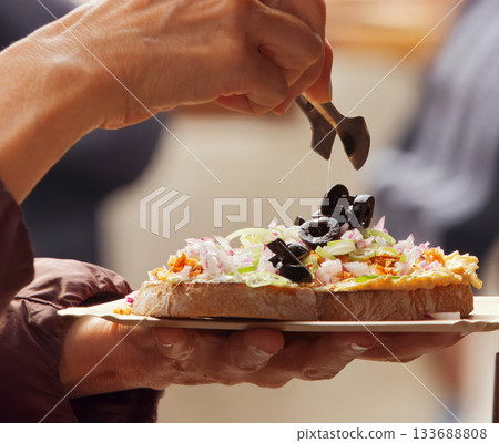 Hand serving fresh bread with olives and onions Hand serving fresh bread with olives and onions 133688808
