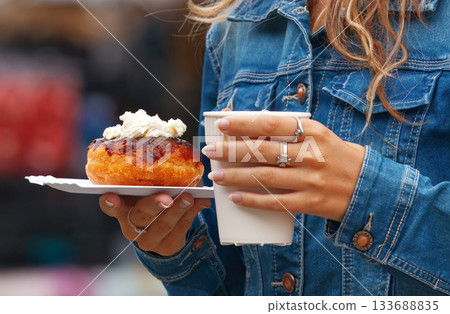 Young woman holding donut and coffee at market 133688835