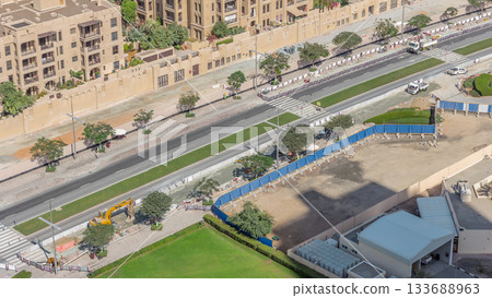 Excavator, truck and grader working at road construction site in Dubai downtown timelapse 133688963