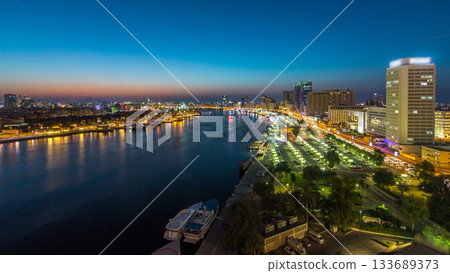 Dubai creek landscape day to night timelapse with boats and ship near waterfront 133689373
